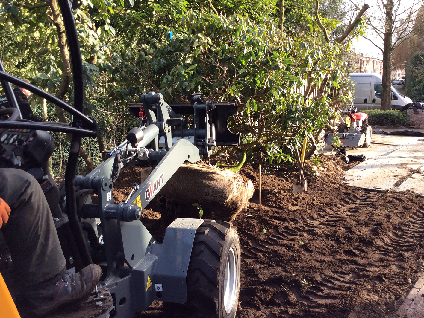 Beplanting grote struiken met professionele graafmachine bij grote woning in Malle